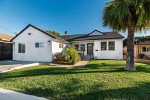 Modern white single-story home with black trim and palm tree